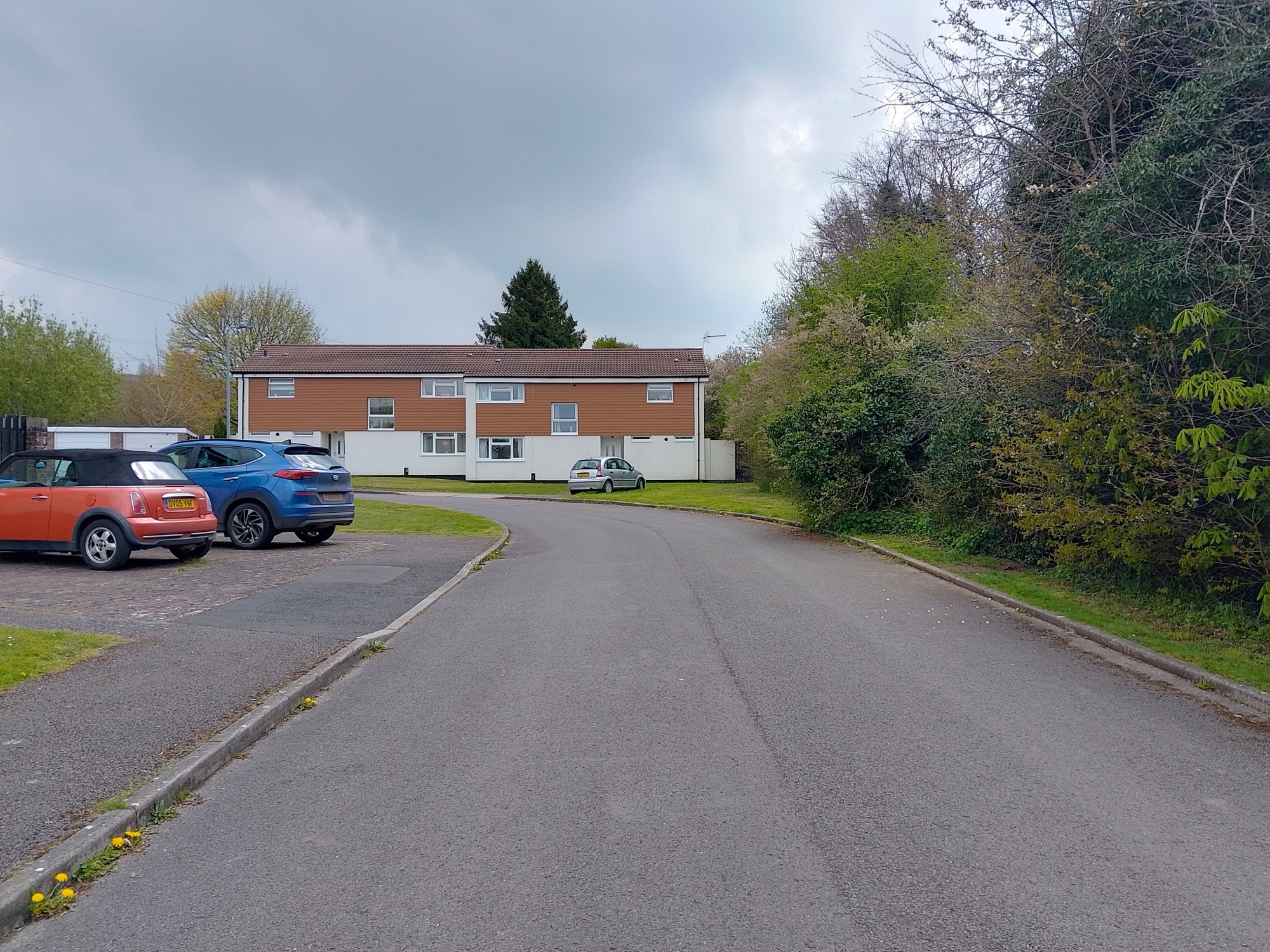 A terrace of 1960s-style married quarters on Nelson Road, Bulford Camp, Wiltshire — white render below, tile-hung cladding above, under a grey sky.