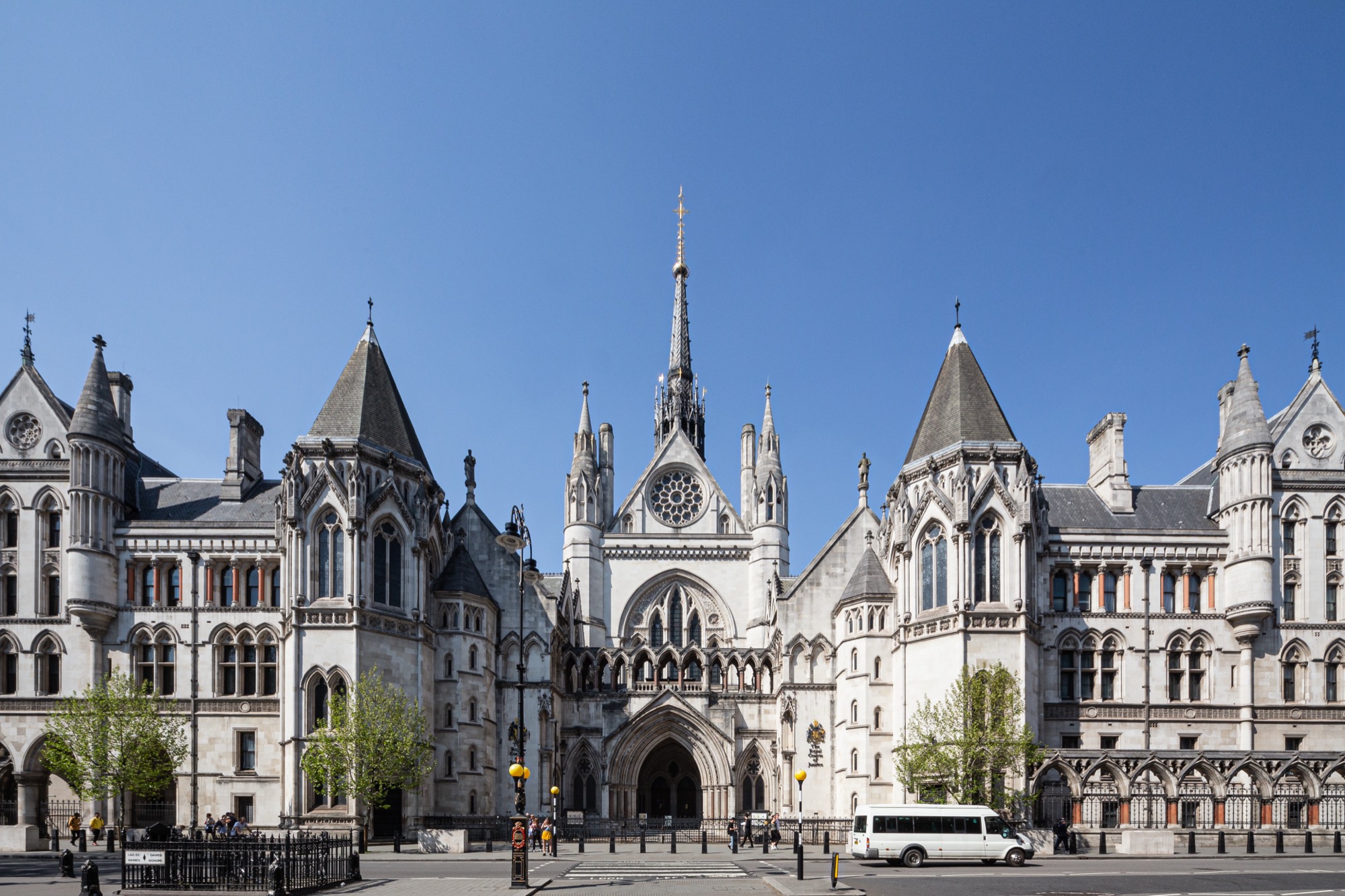The Royal Courts of Justice on the Strand, London — the Victorian Gothic main front under a clear blue sky.