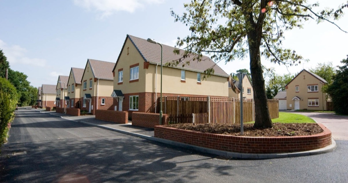 A street of modernised Service Family Accommodation on the Marchwood estate, Hampshire — brick and render houses along a fresh cul-de-sac under a blue sky.
