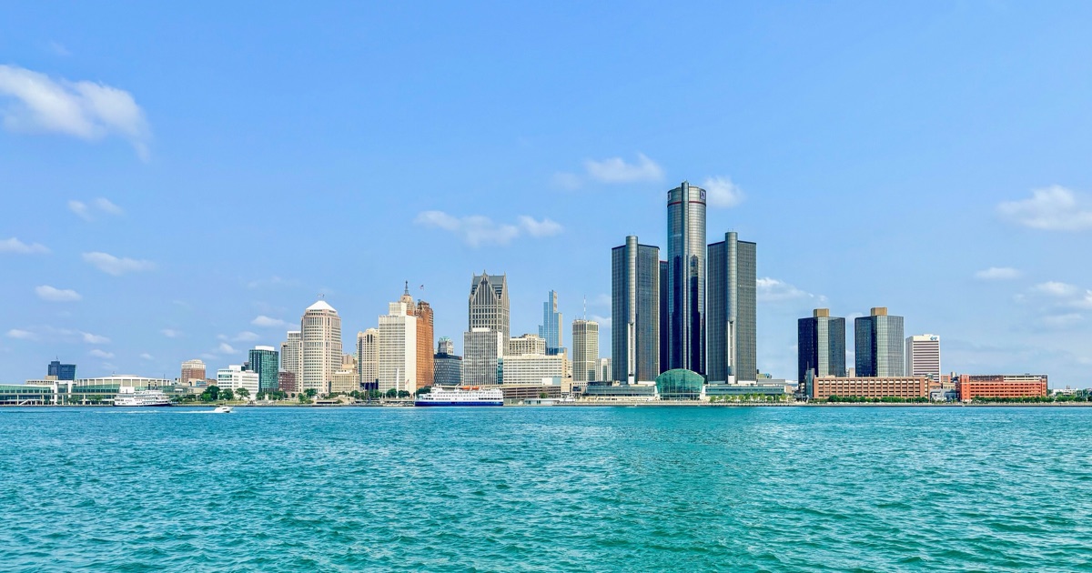 Downtown Detroit's skyline seen across the Detroit River from Windsor, Ontario on a clear summer morning, with the cylindrical towers of the Renaissance Center at right.