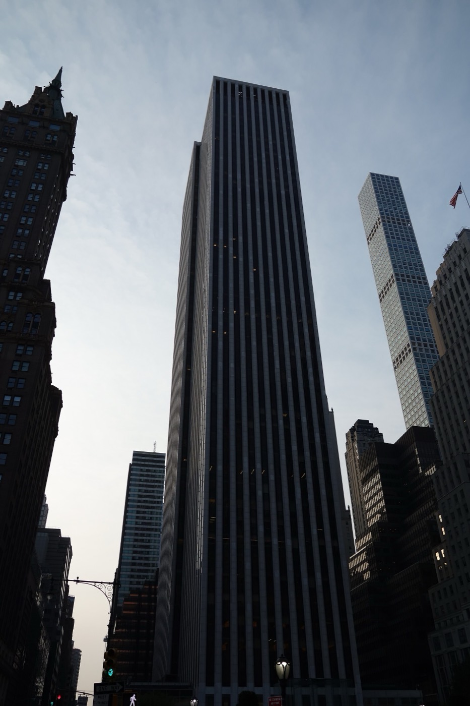 The General Motors Building at 767 Fifth Avenue seen from Grand Army Plaza — a white marble tower in vertical bands of stone and dark glass, rising above the trees at the corner of Central Park.