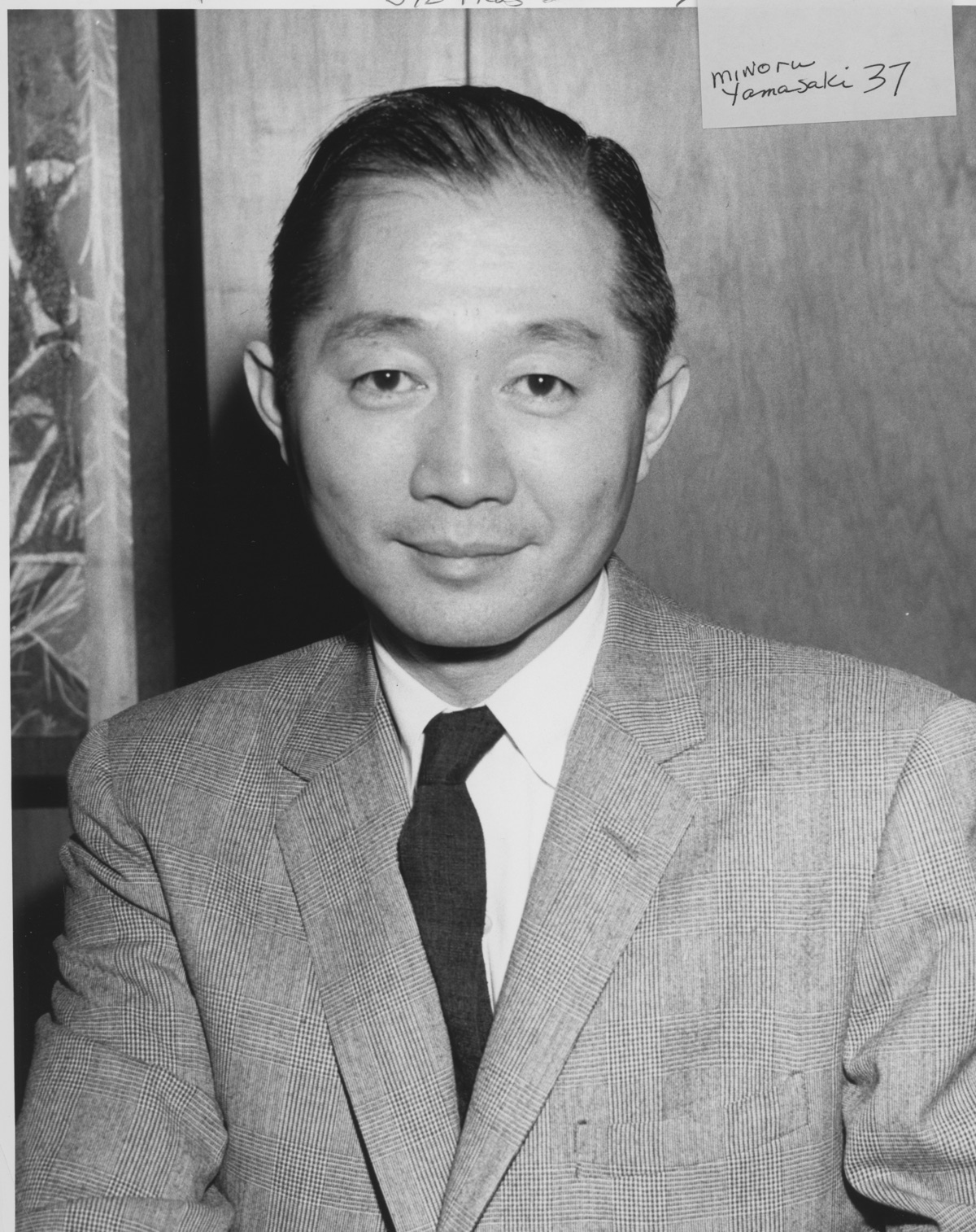 Architect Minoru Yamasaki in 1959, seated at a table in a suit and glasses, photographed in Seattle.