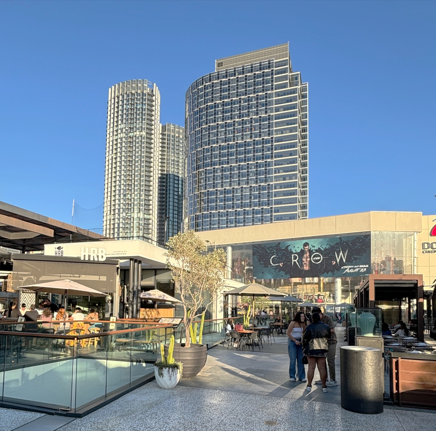 The two Park Elm towers at Century Plaza in August 2024 — rounded triangular glass high-rises beside the older Constellation Place tower, seen from Westfield Century City.