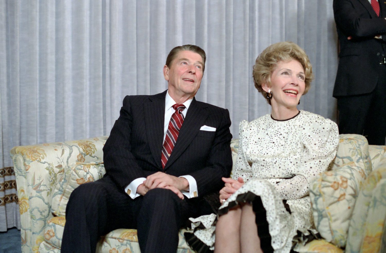 Ronald and Nancy Reagan seated on a floral couch in a Century Plaza Hotel suite, watching election returns on the night of 6 November 1984.