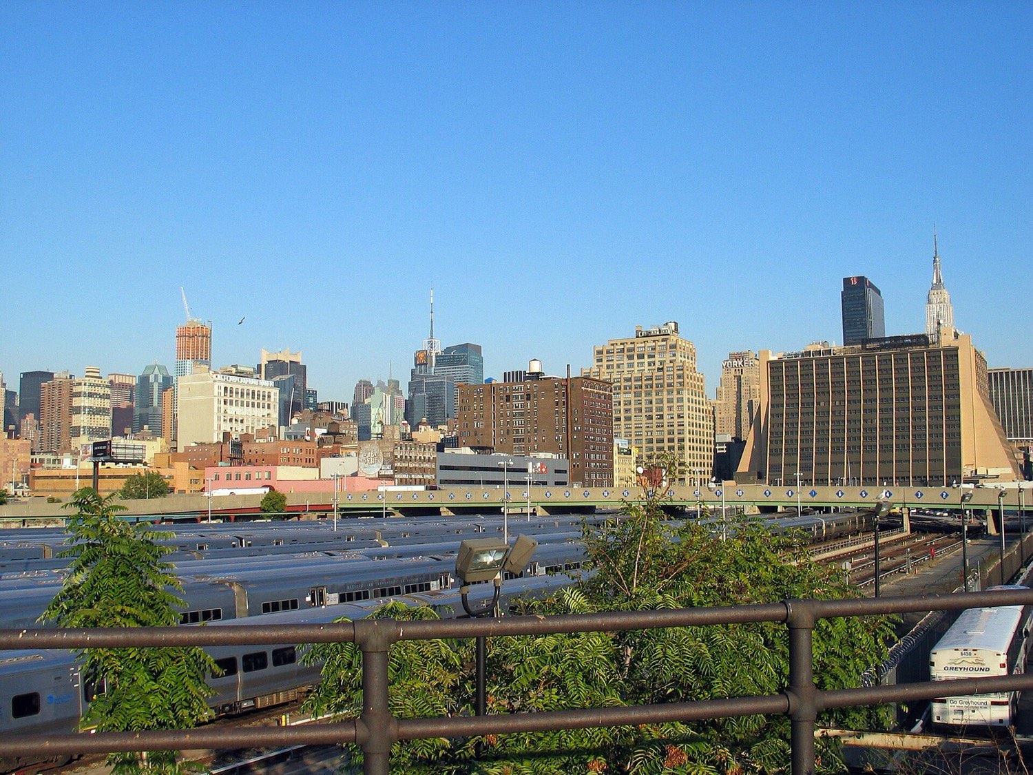 A view from the derelict High Line in 2005 over the open West Side rail yard, rows of commuter trains parked below, the Empire State Building and Midtown on the horizon.