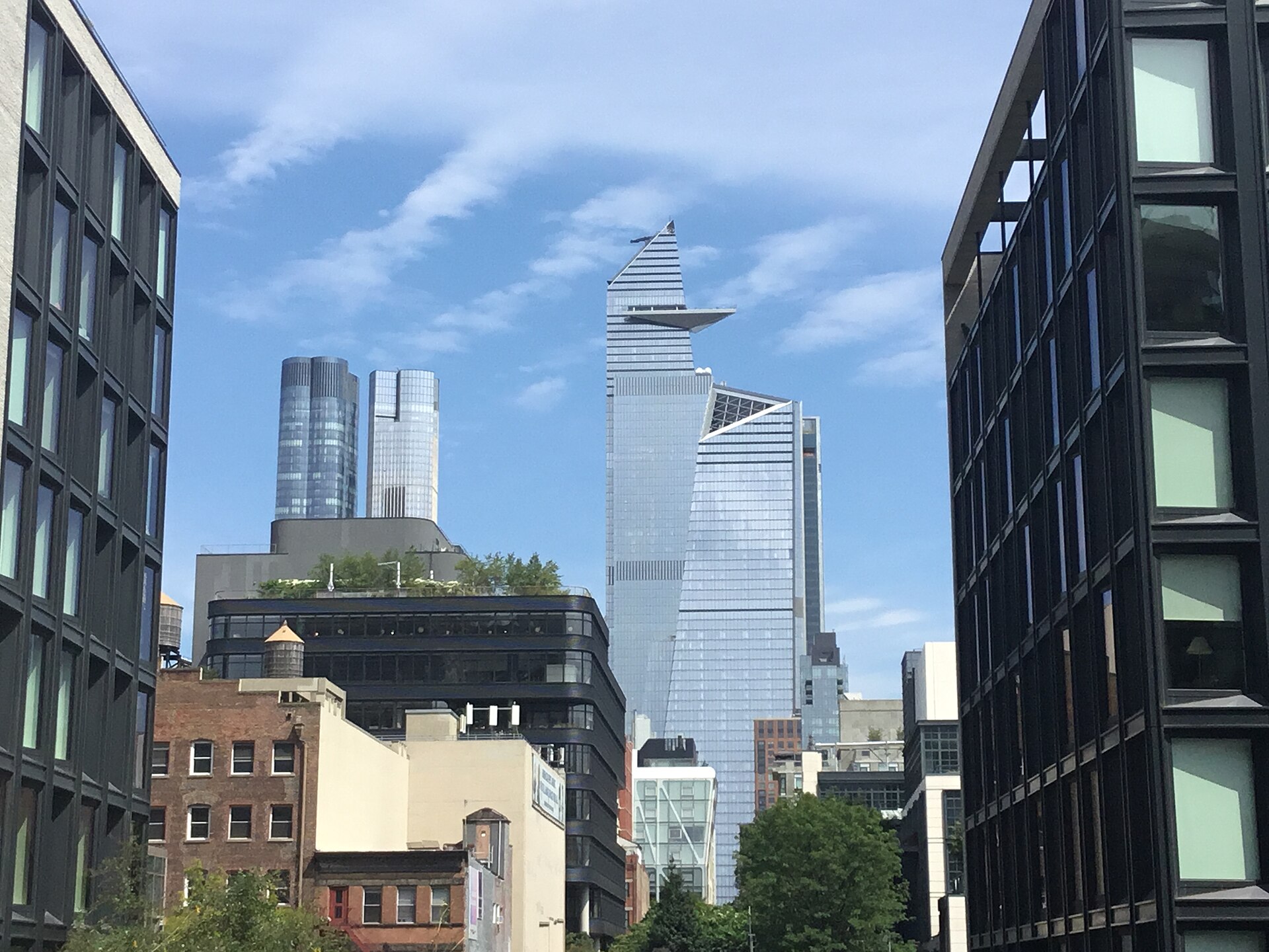 The Hudson Yards towers seen from the northern end of the High Line, glass buildings rising directly above the park’s planted walkway.