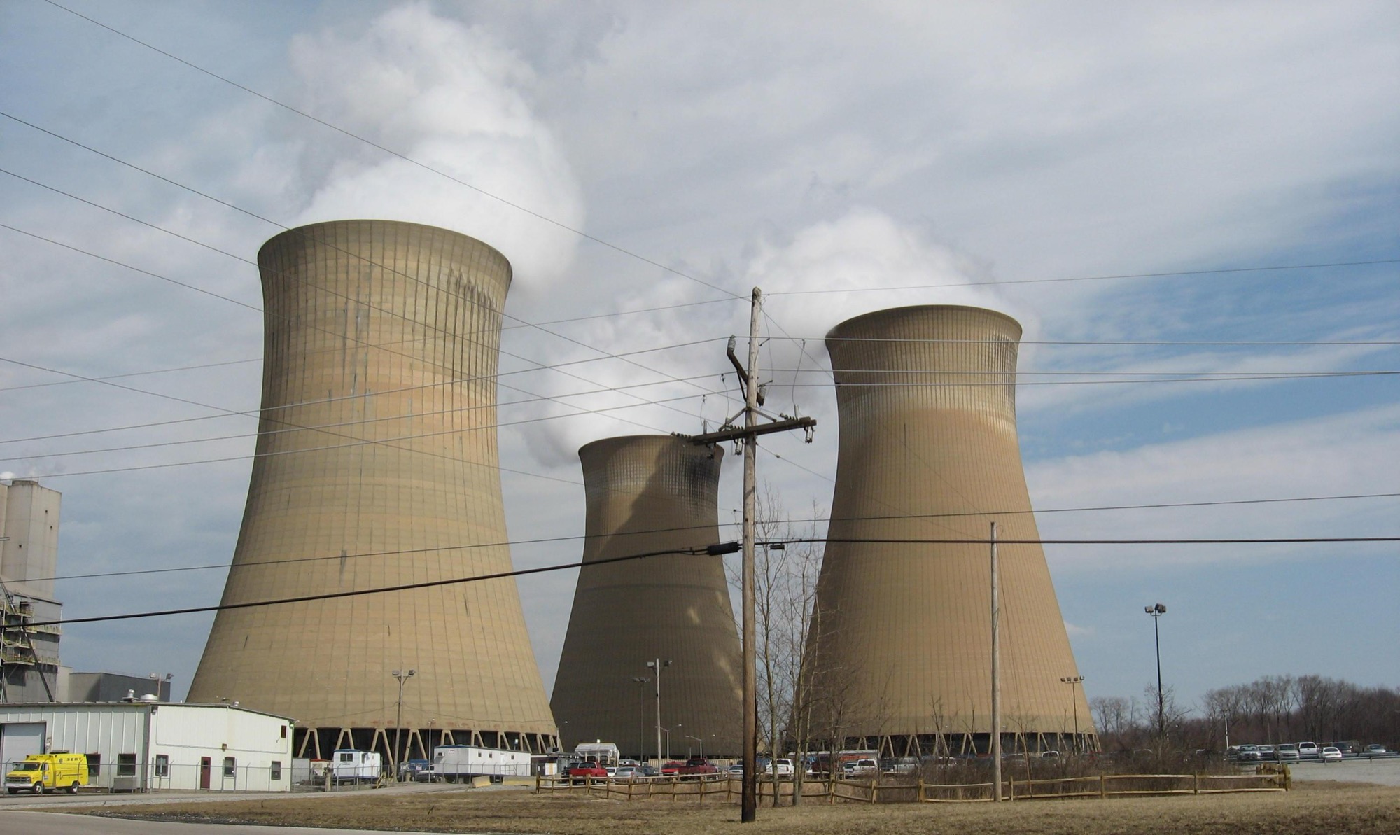 The three cooling towers of the Homer City Generating Station in Pennsylvania venting steam, power lines crossing the frame.