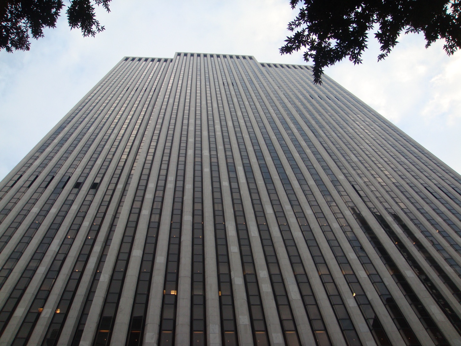 The General Motors Building at 767 Fifth Avenue seen from a high angle, its white marble piers running the full height of the tower between dark bands of glass.