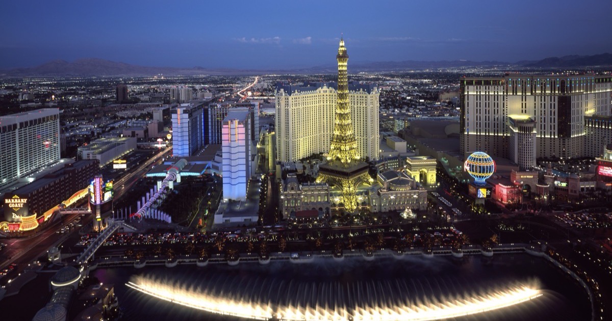 Aerial twilight view of the Las Vegas Strip showing the Bellagio’s fountain lake in the foreground and the Eiffel Tower replica at Paris Las Vegas across the street.