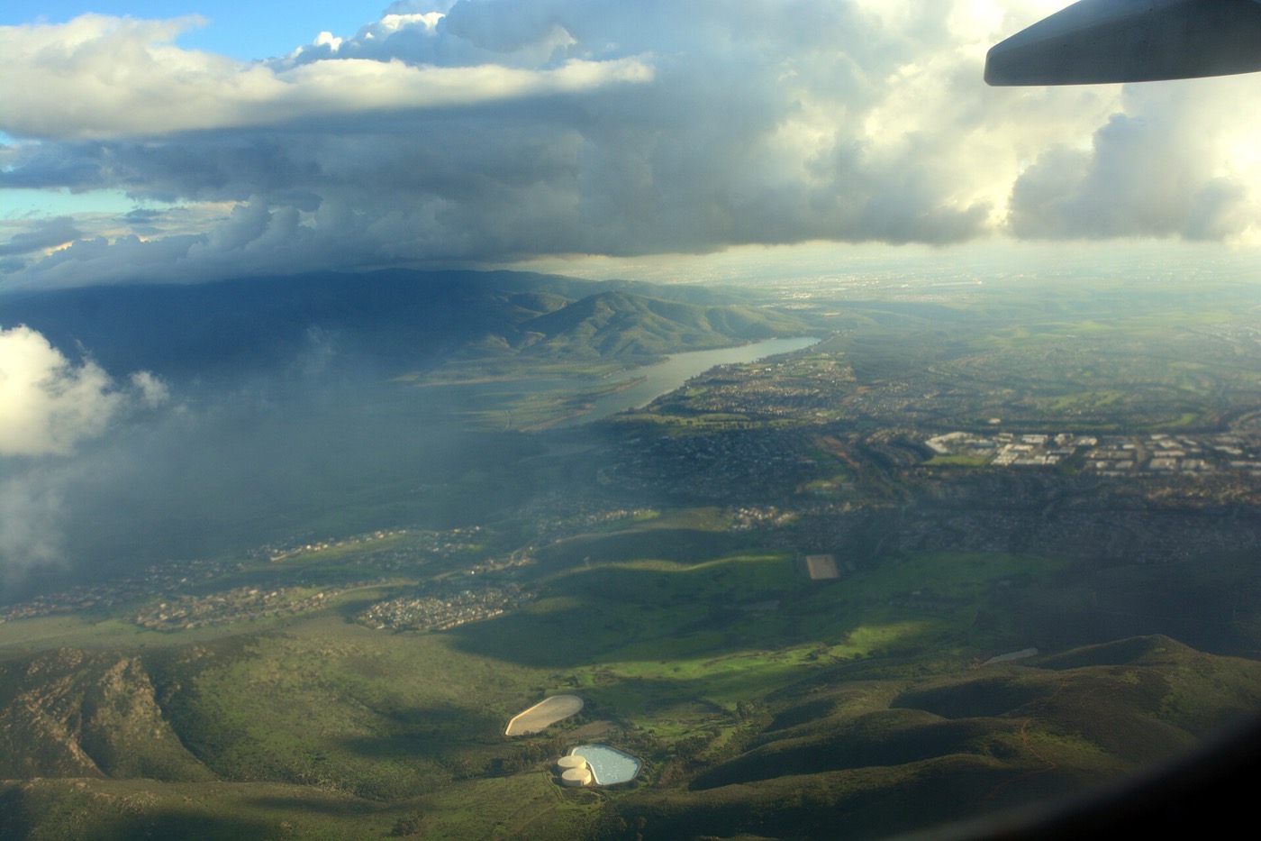 Aerial view from a small plane looking south-east over the Otay River valley, with Lower Otay Lake below and storm clouds overhead.