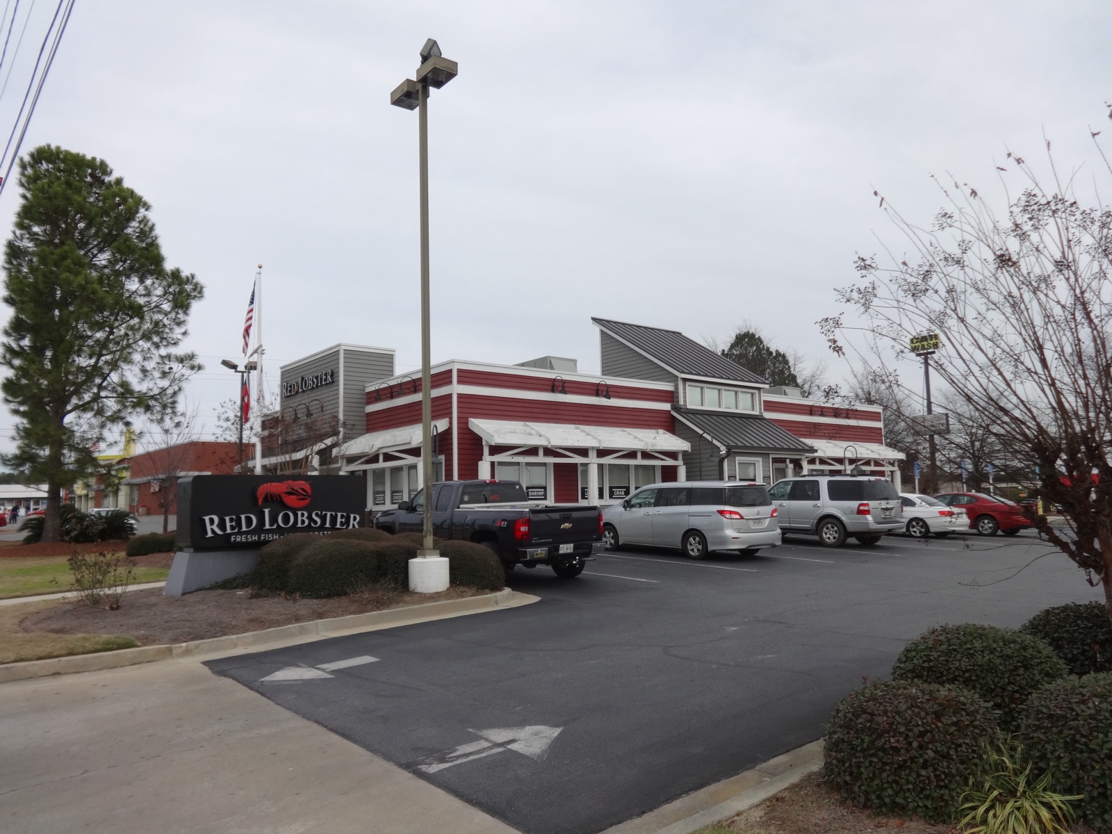 A red and white Red Lobster restaurant building in Tifton, Georgia, with a stone-based monument sign bearing the lobster logo in the foreground and several cars parked outside.