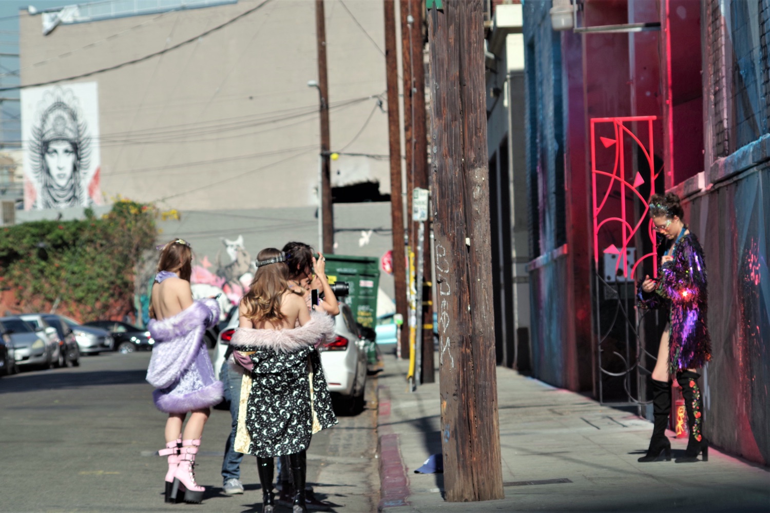 A warehouse-lined street in the Arts District of Los Angeles — brick facades, murals and parked cars under a bright sky.
