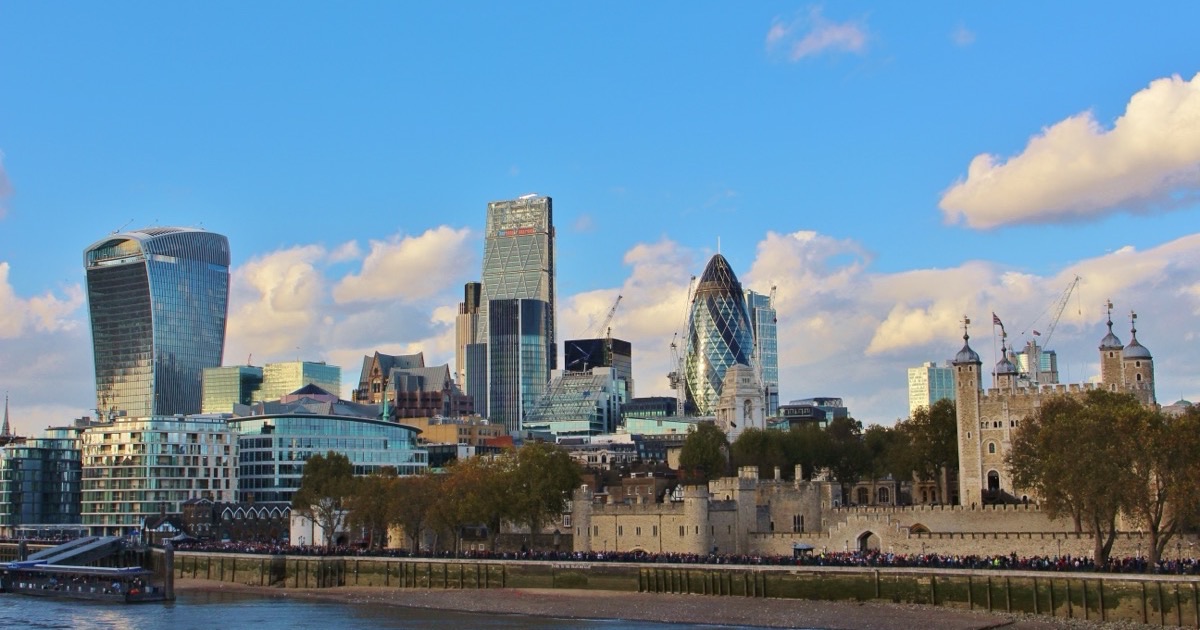 The City of London skyline — the Walkie Talkie, Cheesegrater and Gherkin towers rising behind the Tower of London on the Thames.