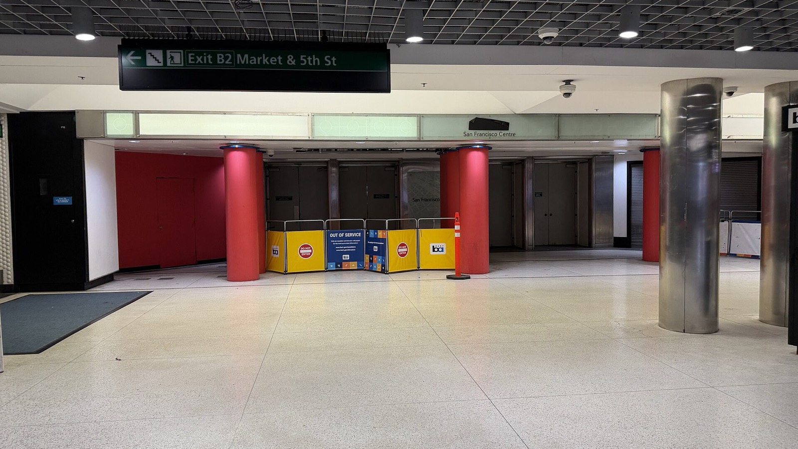 The mall entrance inside BART’s Powell Street station in February 2026 — doors shut behind yellow OUT OF SERVICE barricades, under a sign reading Exit B2, Market & 5th St, with a small San Francisco Centre nameplate above.