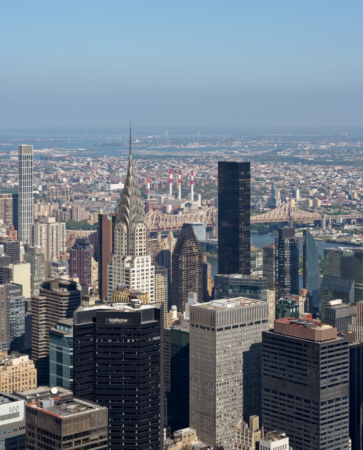 The Chrysler Building’s stainless steel crown seen from above and to the west from the Empire State Building, its triangular windows and arched setbacks catching afternoon light over the surrounding Midtown blocks.