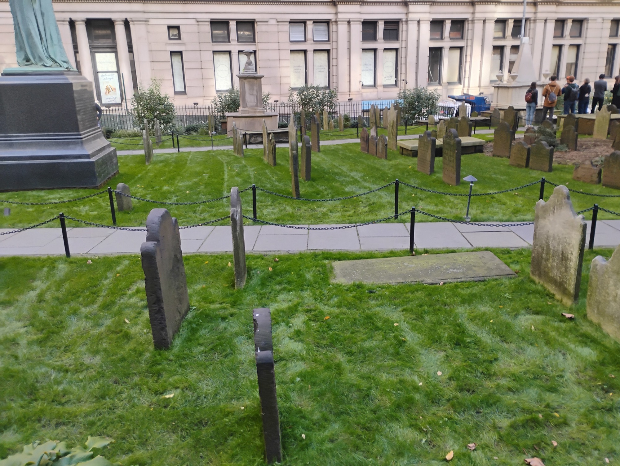 Trinity's churchyard: eighteenth-century headstones on green lawn, office facades rising directly behind the burial ground.
