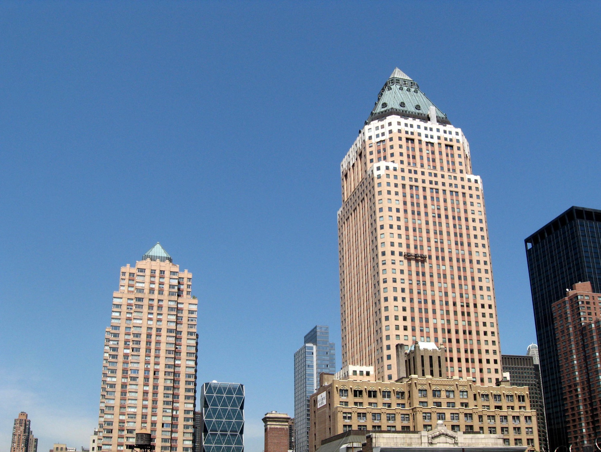 Worldwide Plaza at 825 Eighth Avenue seen from a nearby rooftop in May 2008, its copper pyramid roof against a hazy sky, with the Hearst Tower and Random House Tower behind it.