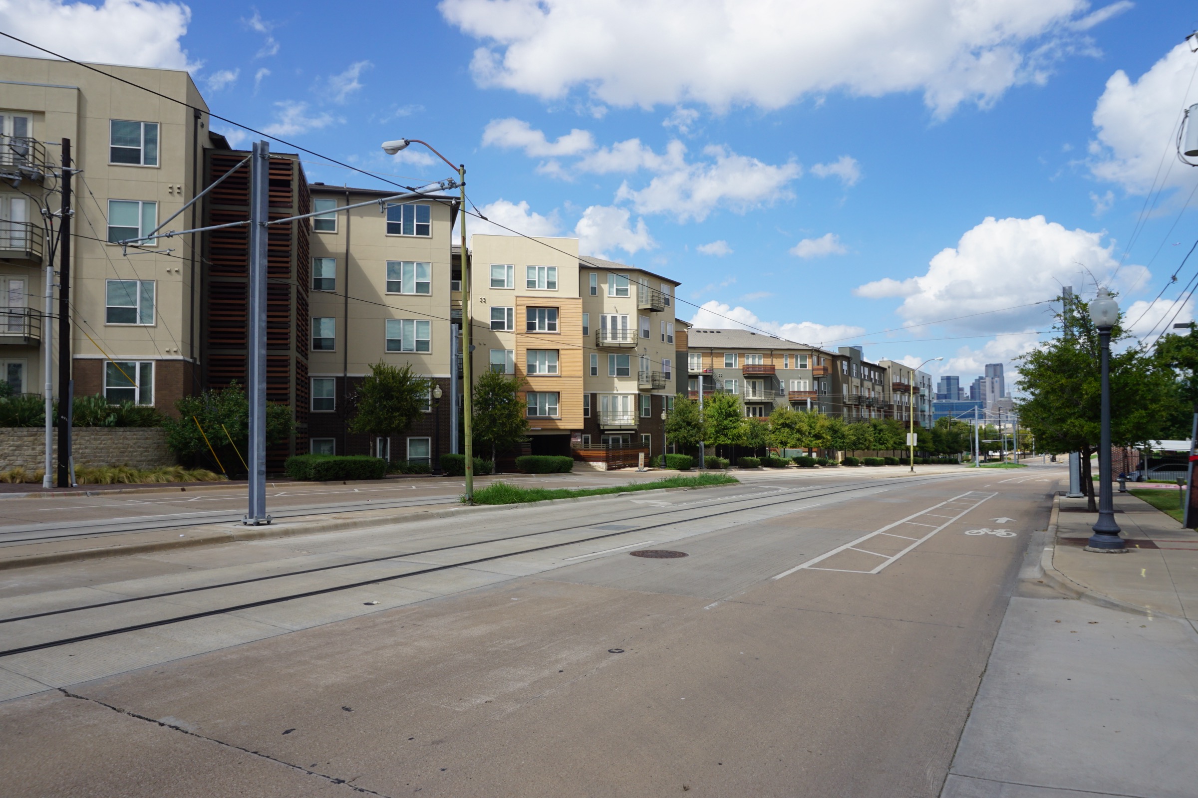 Apartment blocks along Zang Boulevard in Oak Cliff, Dallas, with the downtown skyline small at the end of the street.
