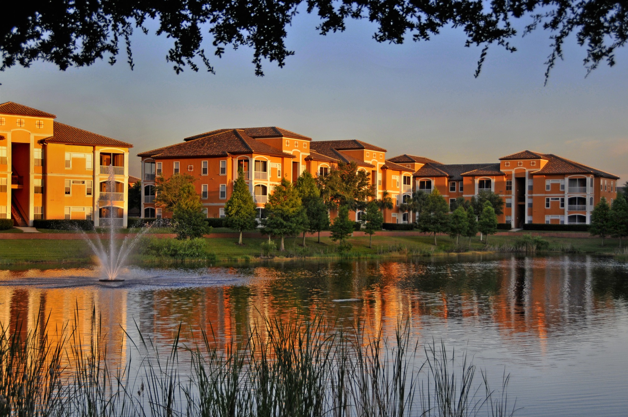 A garden-style apartment complex in Orlando, Florida at golden hour — Mediterranean-style buildings and a fountain reflected in a lake.